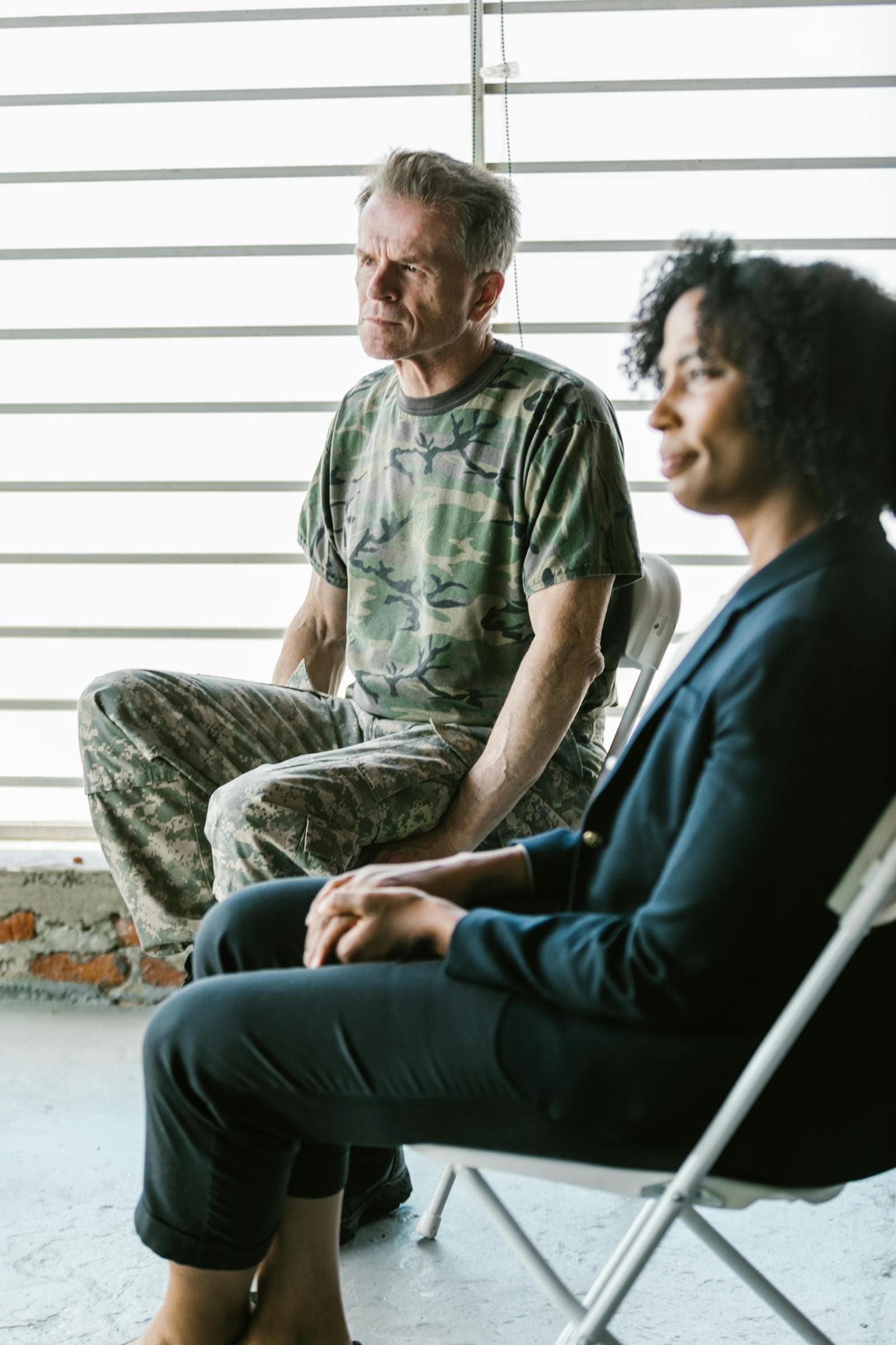 A military veteran in conversation with a counselor or care advisor at home.